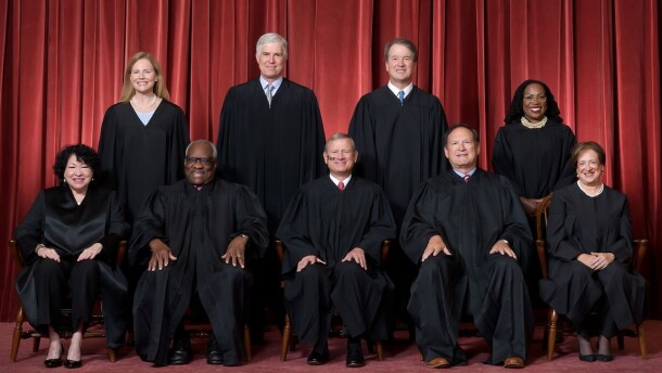 Formal group photograph of the Supreme Court as it was been comprised on June 30, 2022 after Justice Ketanji Brown Jackson joined the Court. The Justices are posed in front of red velvet drapes and arranged by seniority, with five seated and four standing. Seated from left are Justices Sonia Sotomayor, Clarence Thomas, Chief Justice John G. Roberts, Jr., and Justices Samuel A. Alito and Elena Kagan. Standing from left are Justices Amy Coney Barrett, Neil M. Gorsuch, Brett M. Kavanaugh, and Ketanji Brown Jackson. Credit: Fred Schilling, Collection of the Supreme Court of the United States