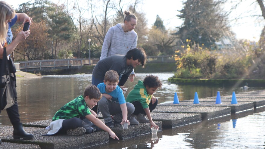 Four students and a chaperone look into a pond.