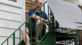 Craig Keenan installs a microconverter to pair with his new solar panel from Bright Saver on his back steps on Friday, Aug. 1, 2025, in Baltimore.