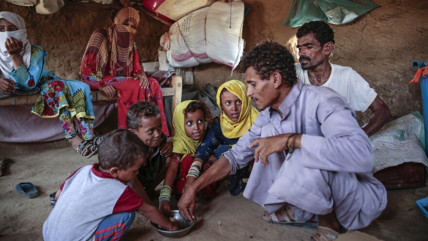 A man feeds children a paste made of green leaves, in Aslam, Yemen, northwest of the capital Sanaa. It's traditionally a side dish, but with the country facing extreme food shortages, it has become the main meal for some.