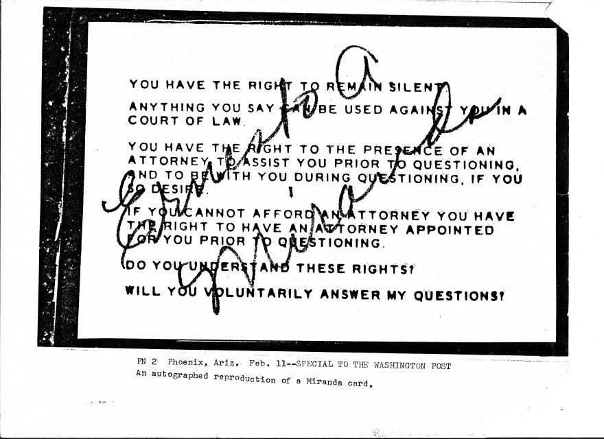 A small card with typed black and white letters and a signature over the top