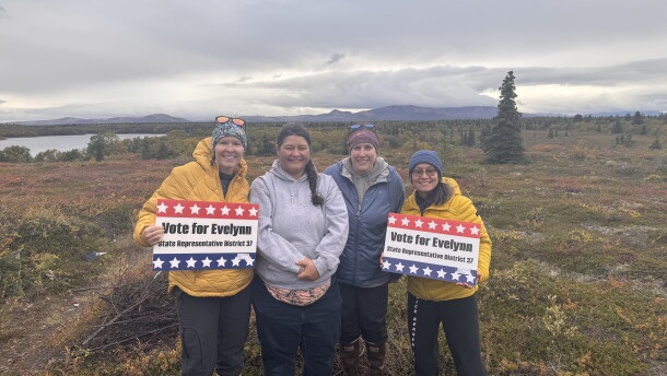four women standing in a line against a natural background 