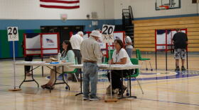 Voter check-in tables and voting booths inside a school gymnasium