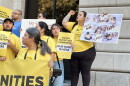 A close up on a crowd protesting with some signs that read, "Our home is here."