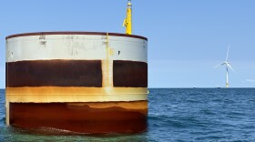 A monopile installed at the site of the Coastal Virginia Offshore Wind project, with one of Dominion Energy's pilot turbines in the background.