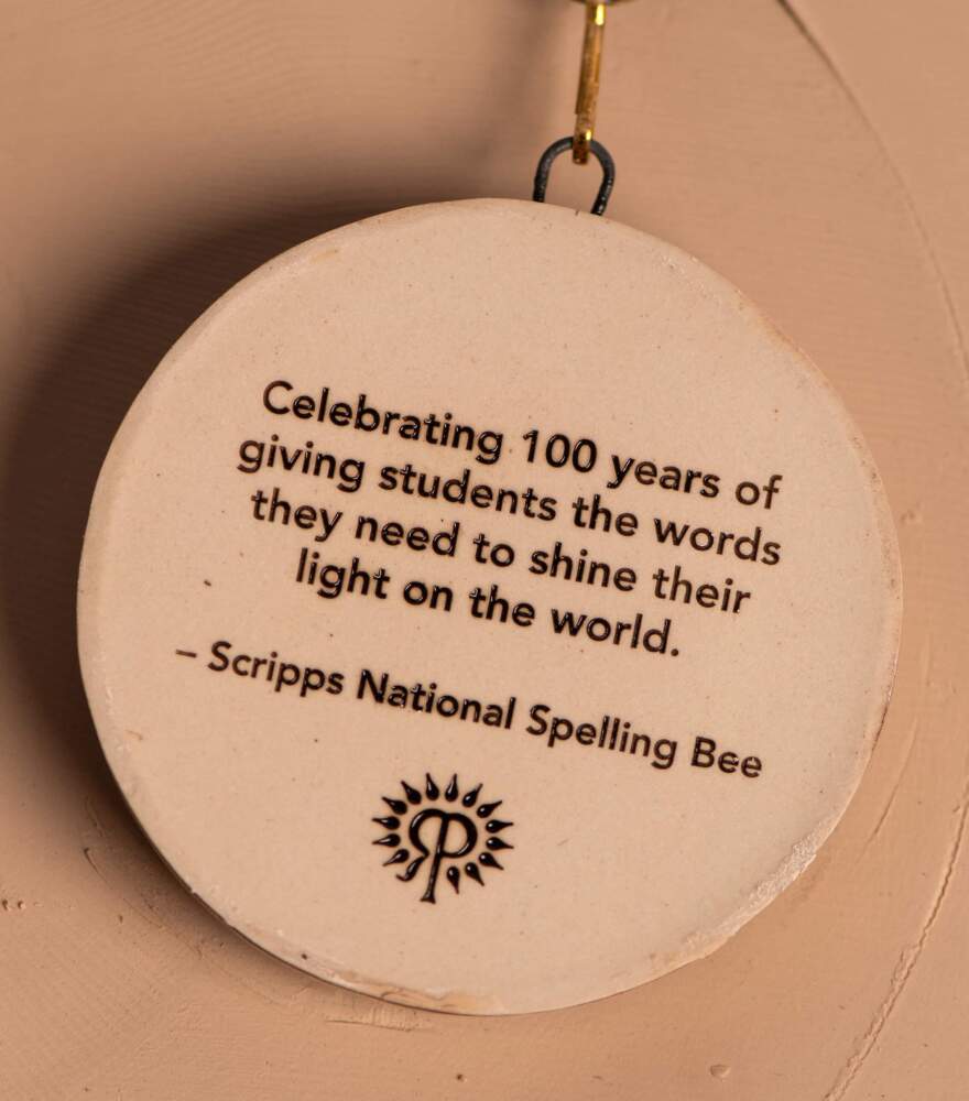 ceramic medallion reading "celebrating 100 years of giving students the words they need to shine their light on the world."