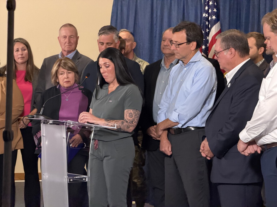 Gov. Bob Ferguson stands with residents and officials as local homeowner describes destruction left behind in summer wildfires. 