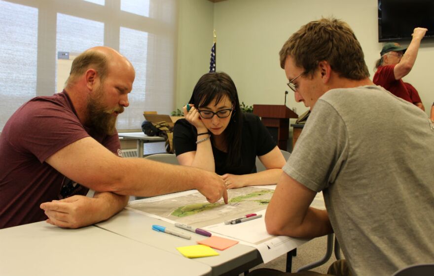 Dave Hutchins (L) and Daniel Hogan look over plans for the cleanup and restoration of the SIlver Bow Creek corridor with Julia Crain, a special projects planner with Butte-Silver Bow county's Superfund Division, June 12, 2018.