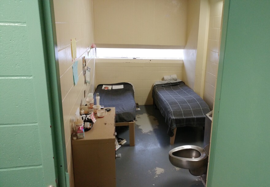 A jail cell in a pod holds at least two beds and a toliet.