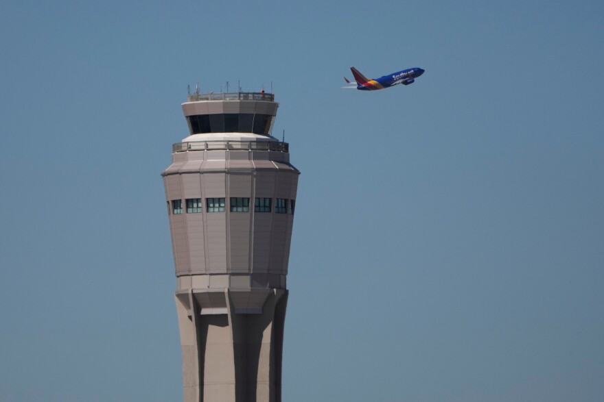 A plane takes off near the air traffic control tower at Harry Reid International Airport, Tuesday, Oct. 7, 2025, in Las Vegas.