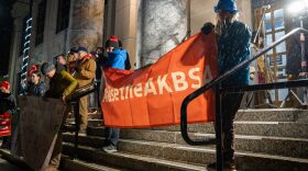 Protestors hold a banner calling for an increase in the base student allocation, a key part of the state’s education funding formula, during a rally at the Alaska State Capitol on Jan. 29, 2024. (Eric Stone/Alaska Public Media)