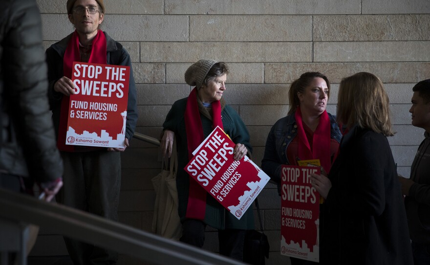 From left, Cory Bushore, Cindy Cole and Jennifer Newman stand in line while waiting to attend the public hearing on Wednesday, November 1, 2017, at City Hall in Seattle. 