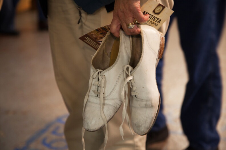 A person stands holding their dancing shoes.