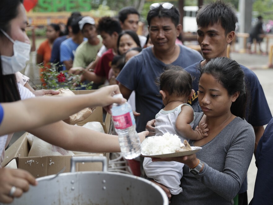 Evacuees receive a meal at an evacuation center at Santa Teresita, Batangas province, on Thursday.