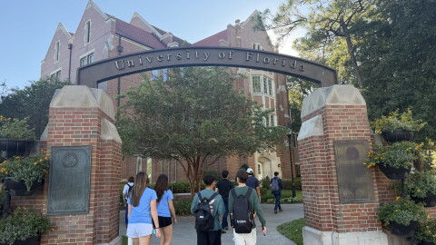 Students walk beneath the University of Florida entrance at the corner of 13th Street and University Avenue.