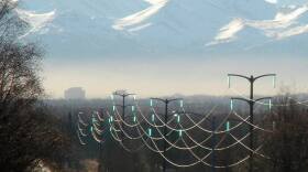Power transmission lines on poles in the foreground, with mountains in the distance.