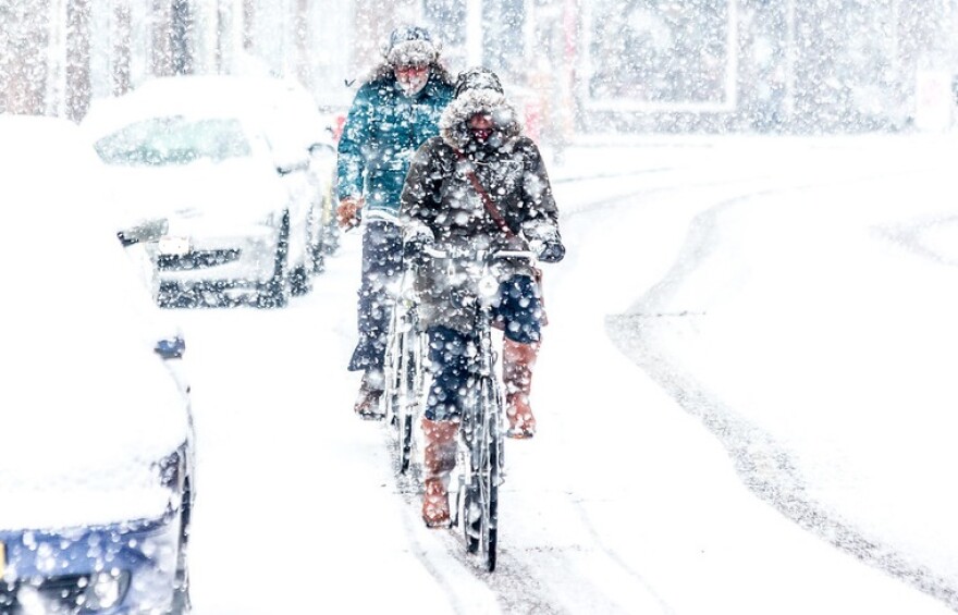 Two people biking on a snowy city street