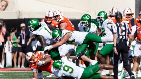 Football players tumble at the end of a play.