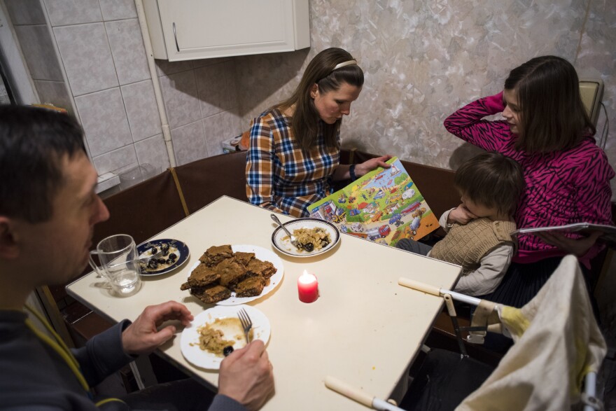 Marina Kluchnikov reads to her youngest child, Sasha, 3, as husband Artyom Kluchnikov looks on and daughter Olenka, 11, reads a book of her own. With Russian troops amassed along Ukraine's border, they worry if an invasion could be imminent.