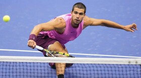 Carlos Alcaraz hits a tennis ball with a racket