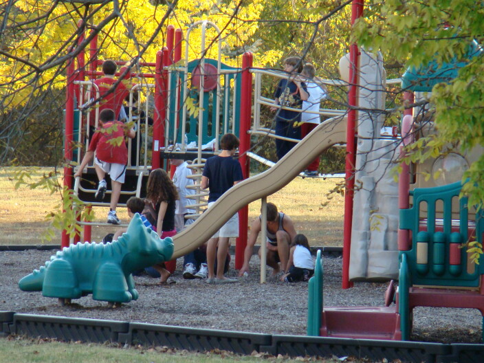 A bunch of children playing and running around a playground at a church party.