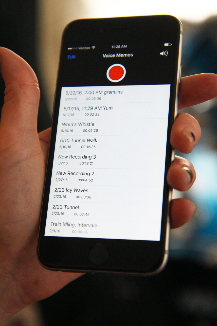 A woman holds up an iPhone with voice memos with names like "gremlins" and "icy waves."