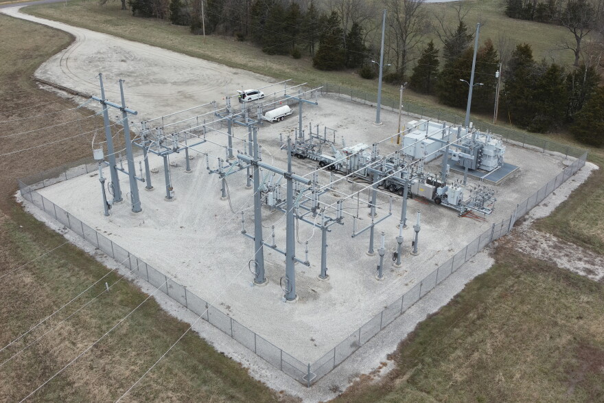 An aerial view of an electric substation. There is a square lot with steel poles and electrical boxes and wires connecting them.