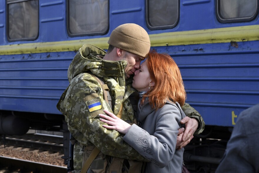 A couple embraces before the woman boards a train leaving for western Ukraine, at the railway station in Kramatorsk, eastern Ukraine, on Sunday. The U.N. refugee agency says nearly 120,000 people have so far fled Ukraine into neighboring countries in the wake of the Russian invasion.