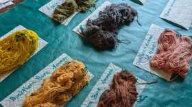 Six different collections of yarn, each a different color, on a table with a green tablecloth