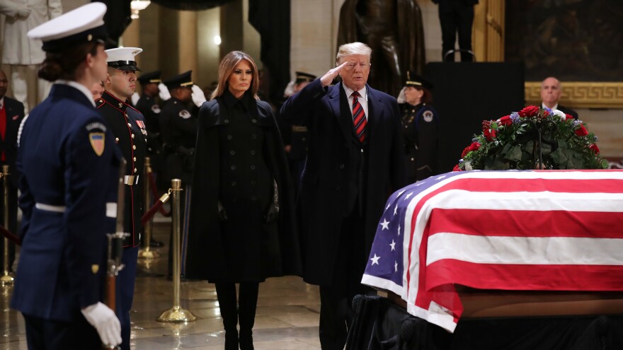 President Trump salutes as he and first lady Melania Trump pay their respects as former President George H.W. Bush lies in state in the U.S. Capitol Rotunda Monday in Washington, D.C.