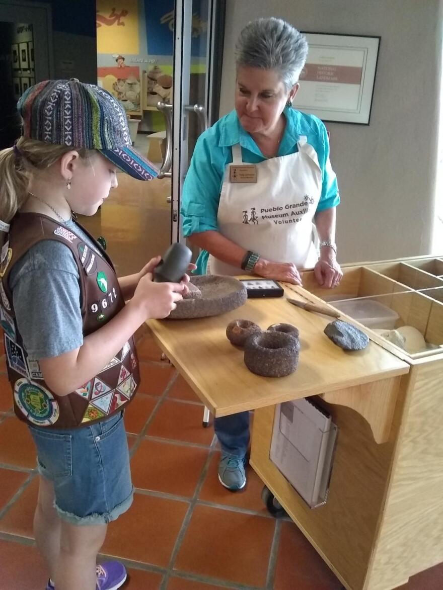 Volunteer Twig Johnson discussing prehistoric artifacts with a girl scout visitor
