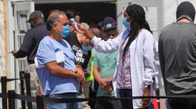 A temperature reading is taken of each person prior to receiving a COVID-19 vaccination by Department of Defense medical personnel at the MDC North vaccine site run by FEMA. On Monday, people 50 and older became eligible for the vaccine statewide.