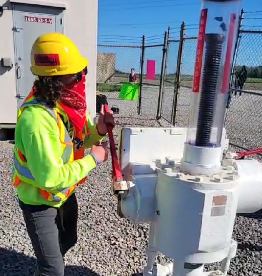 A demonstrator turns a valve at an exposed portion of Enbridge's Line 5 oil pipeline Tuesday in a video posted to Facebook.