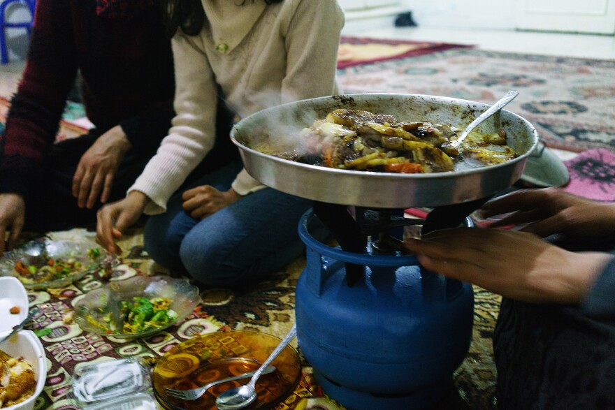 A Syrian woman cooks Aleppo-style kebab on a platter over a propane stove in her apartment in the southern Turkish city of Kilis, near the border with Syria, in December 2015.