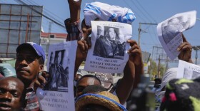Protesters hold up copies of former rebel leader Guy Philippe with a message that reads in creole "We claim Guy Philippe as president of the council" in Port-au-Prince, Haiti, Tuesday, April 2, 2024.