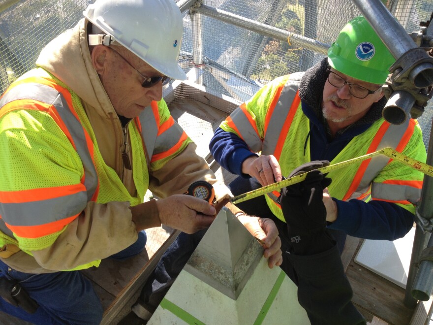 Don Breidenbach, left, and Kendall Fancher take measurements of at the very top of the Washington Monument.