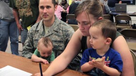 Air Force SSgt. Chris Reed, holding his son Colby, and his wife, Tracy, with son Wesley, seek help at the FEMA office. The couple is looking for housing after their home flooded.