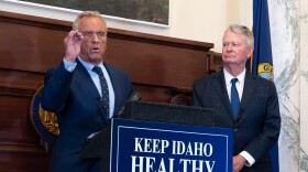 Two men in suits gather around a podium in front of a ceremonial fireplace.
