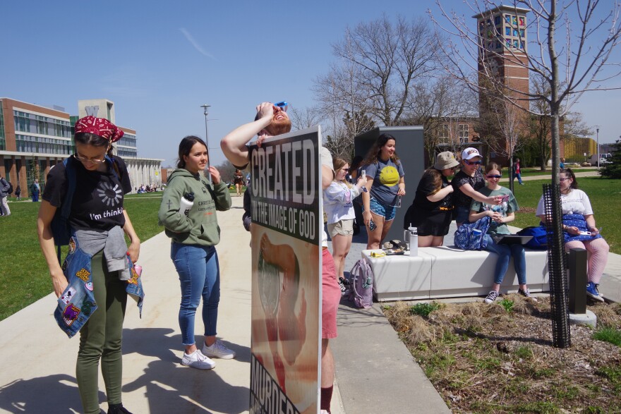 An anti-abortionist borrows a WMU students eclipse glasses to look at the solar eclipse on April 8.