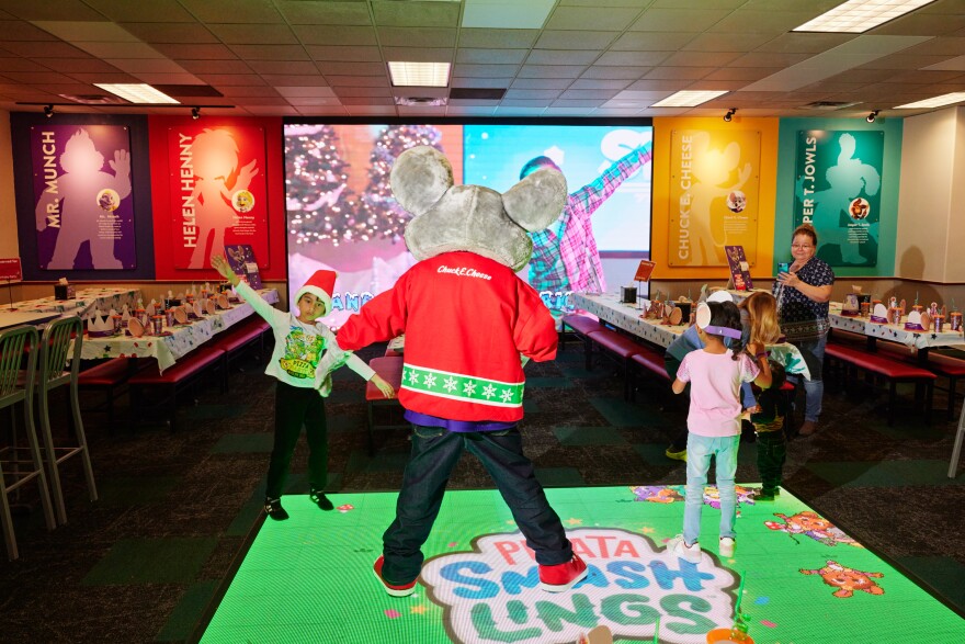 The Chuck E. Cheese mascot shows kids how to do the "Yuletide Slide" dance on the interactive dance floor.