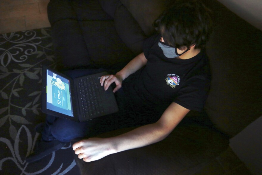 Javin Lujan Lopez, 17, a senior at at Pojoaque High School logs into a remote learning site on his laptop, at his home in Espanola, N.M., Feb. 22, 2021.