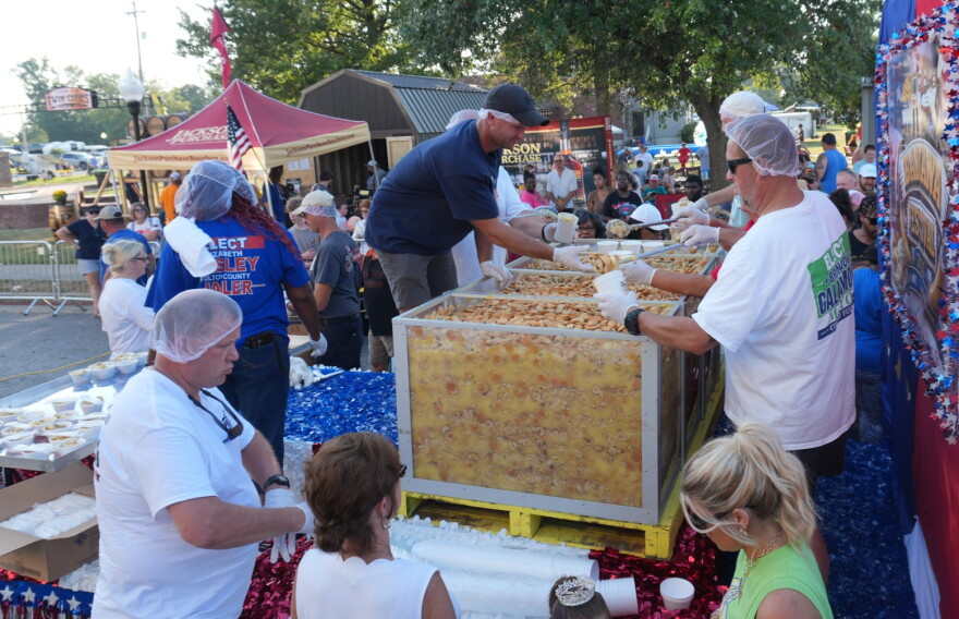 Volunteers fill containers with banana pudding for waiting festival goers
