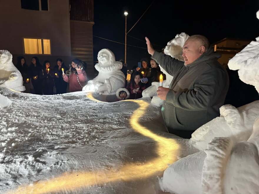 Utqiagvik residents pray next to the snow sculpture during the Blue Christmas event on Dec. 20.