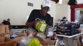 Volunteer Ollie Taylor fills bags with food at the Coconut Grove Crisis Food Pantry, which offers fresh food and meals free of charge on a weekly basis to residents, Tuesday, Aug. 26, 2025, in Miami.