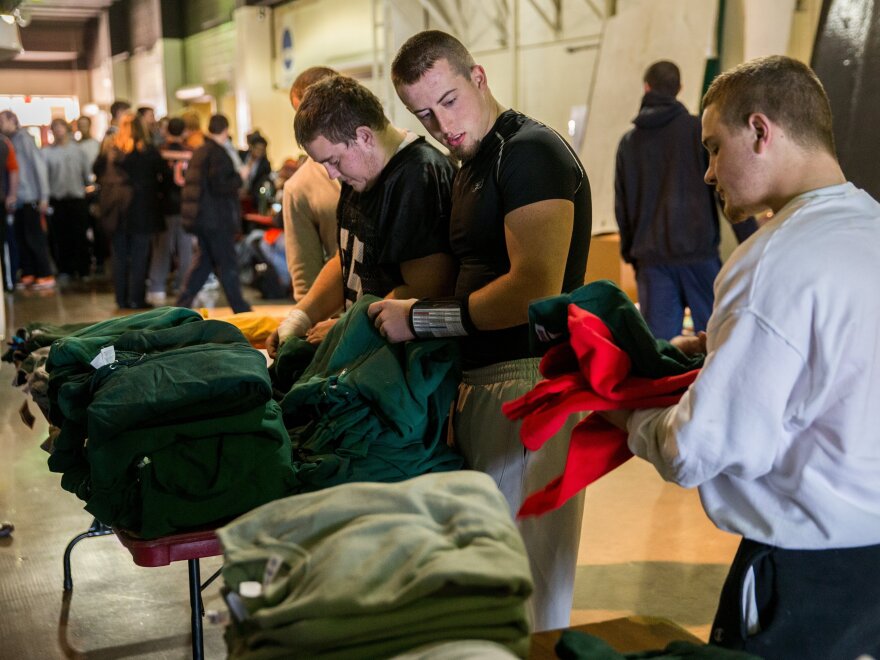 Washington players from left, Nick Sievers, Colton Marshall, and Brogan Brownfield receive donated workout clothes during a break from practice in Normal, Ill., on Tuesday.