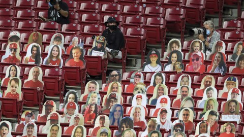 In this Aug. 3, 2020, file photo, photographers practice social distancing while sitting with fan cutouts during a baseball game between the Cleveland Indians and the Cincinnati Reds in Cincinnati.