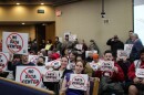 People in city hall chambers hold posters that say no data center 