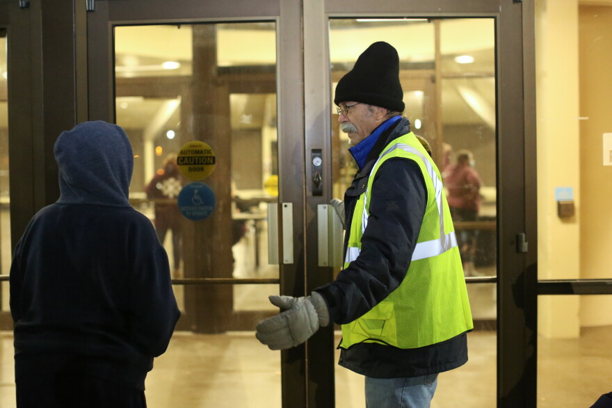 A volunteer invites someone into Wheeler Pavilion at the Lane Events Center, one of several sites that are part of the Egan Warming Centers.