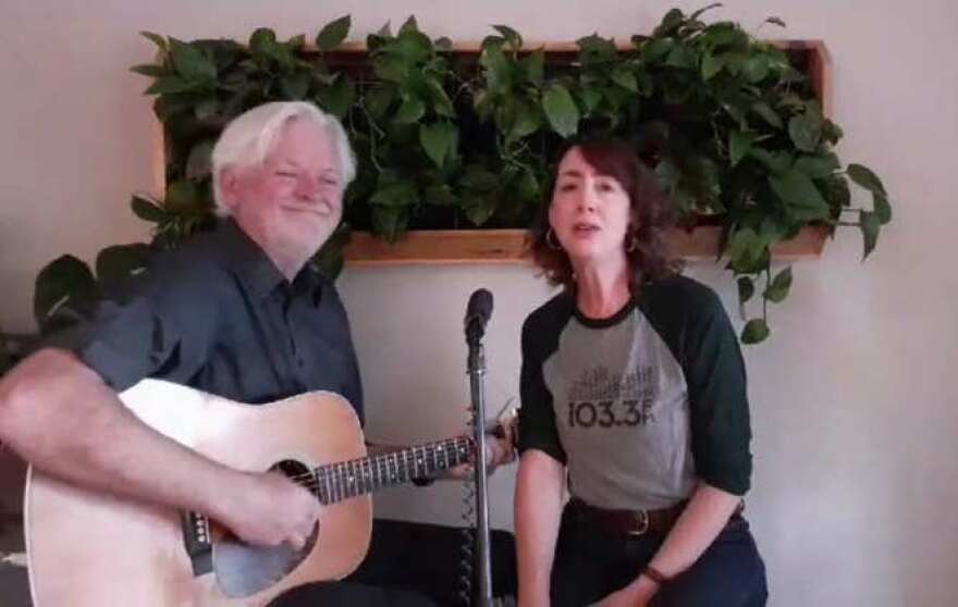 Man playing guitar and woman singing into a microphone