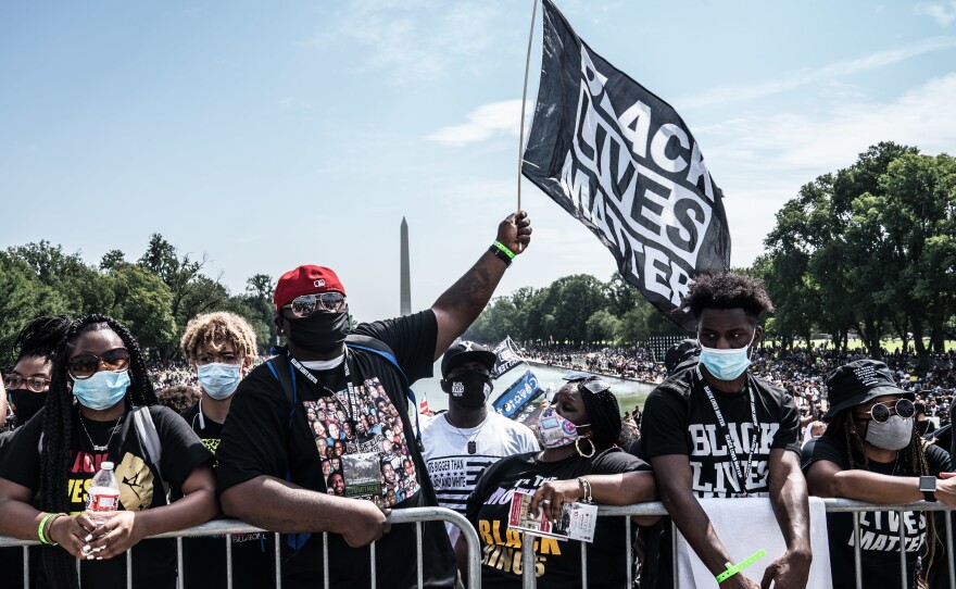 People wait for the speakers to start around the Lincoln Memorial Reflecting Pool.